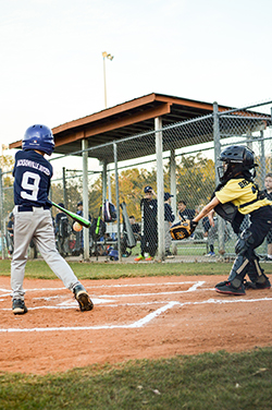 Young boy in blue helmet and jersy swinging a bat to hit a ball at a baseball game.