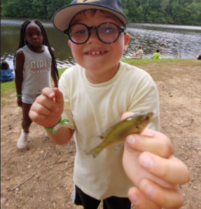 Boy with small fish with girl looking on in background