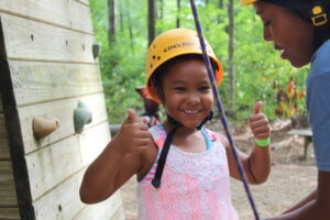 child in a helmut making thumbs up signs 