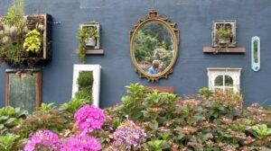 A blue wall in a flower garden with a mirror reflecting My Best Friend