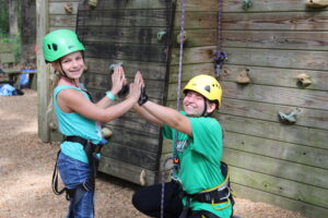 eastern center campers high five by the climbing wall